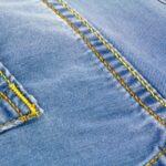 Zbliżenie na niebieski denim z żółtym, wzmacniającym stebnowaniem