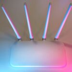Biały router Wi‑Fi z czterema antenami w niebiesko-różowym świetle