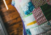 Patchwork jako pamiętnik rodziny: co mówią stare kołdry zszywane z resztek tkanin Zbliżenie na kolorową kołdrę patchworkową z różnymi wzorami i fakturami