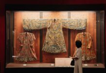 Tradycyjne chińskie szaty w muzeum oglądane przez zwiedzającego