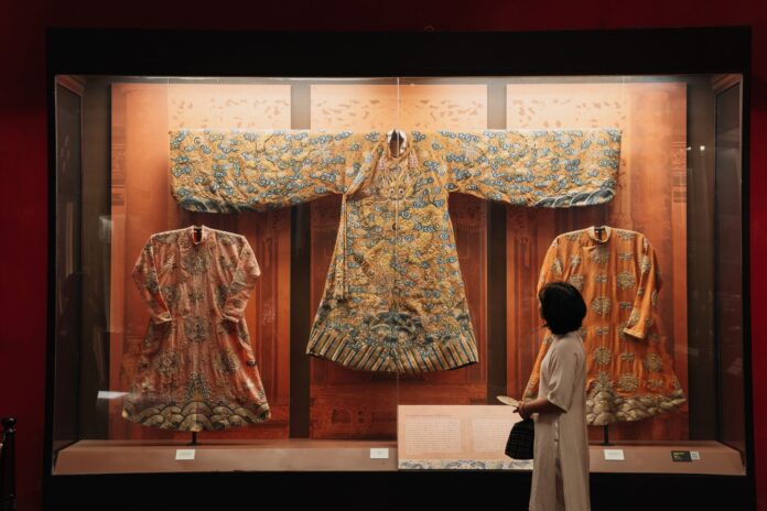 Tradycyjne chińskie szaty w muzeum oglądane przez zwiedzającego Tradycyjne chińskie szaty w muzeum oglądane przez zwiedzającego